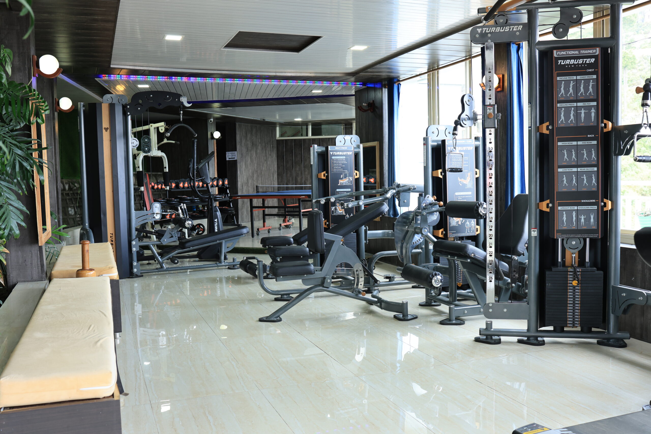 Modern gym with fitness equipment and large windows offering scenic mountain views at Shivalaya Resort by botanix