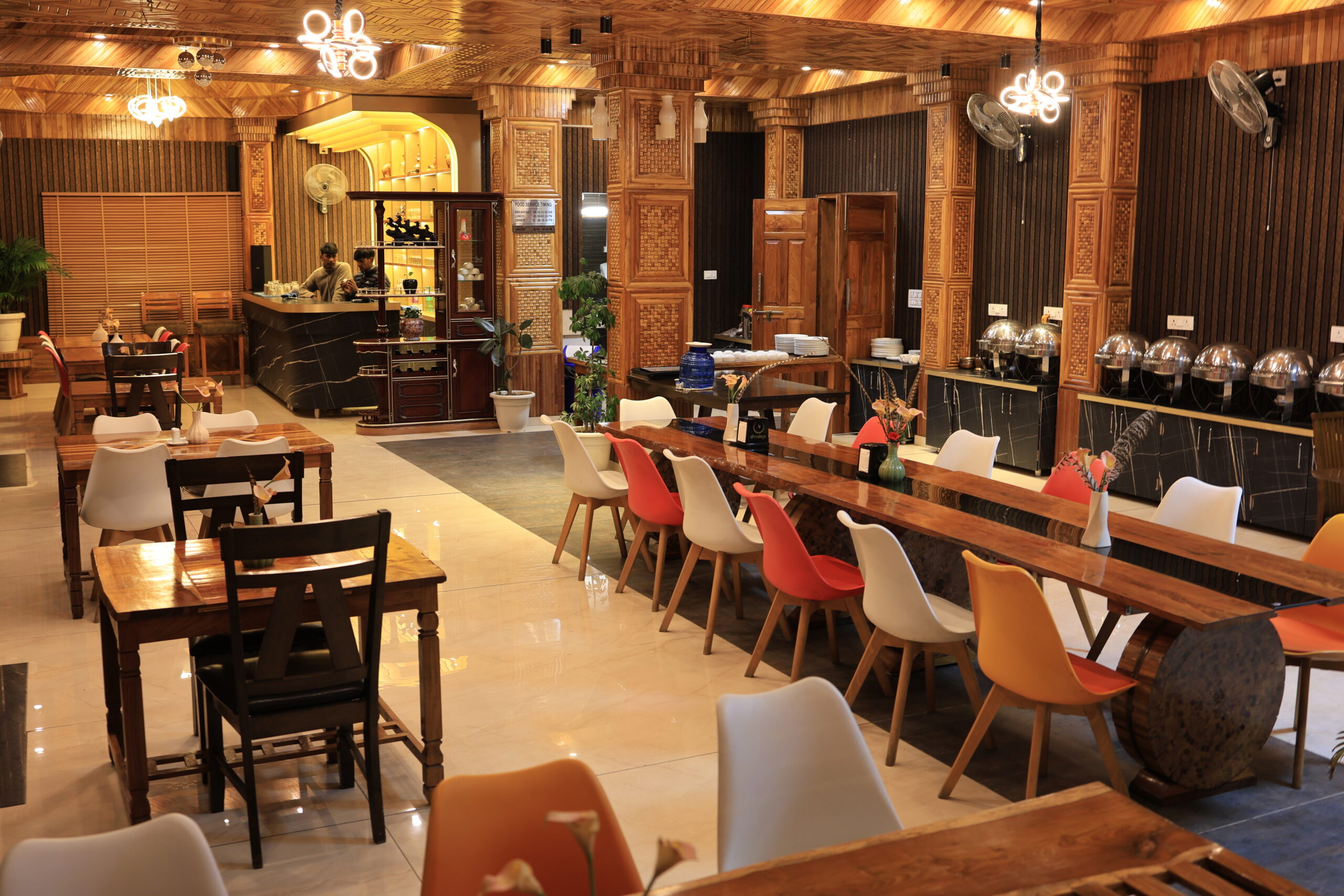 Elegant resort dining hall with wood-paneled ceiling, long wooden communal table and colourful chairs at Shivalaya Resort by Botanix